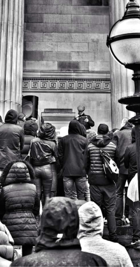 A diverse crowd outside St George's Hall in Liverpool, engaged in a spoken word performance by James Bongo.
