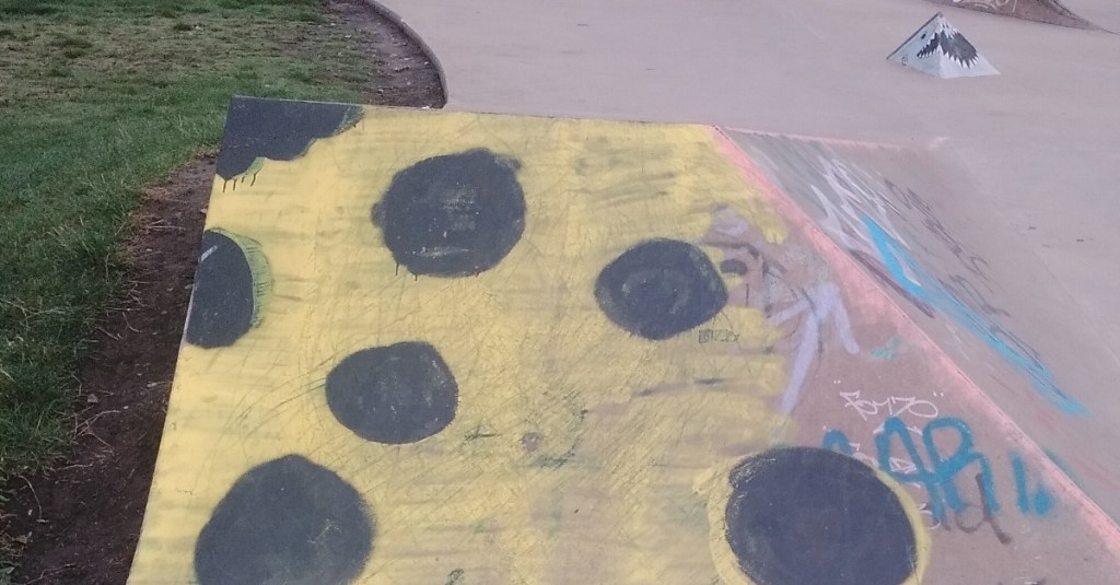 Textural exploration of spray can on concrete, yellow with black dots.