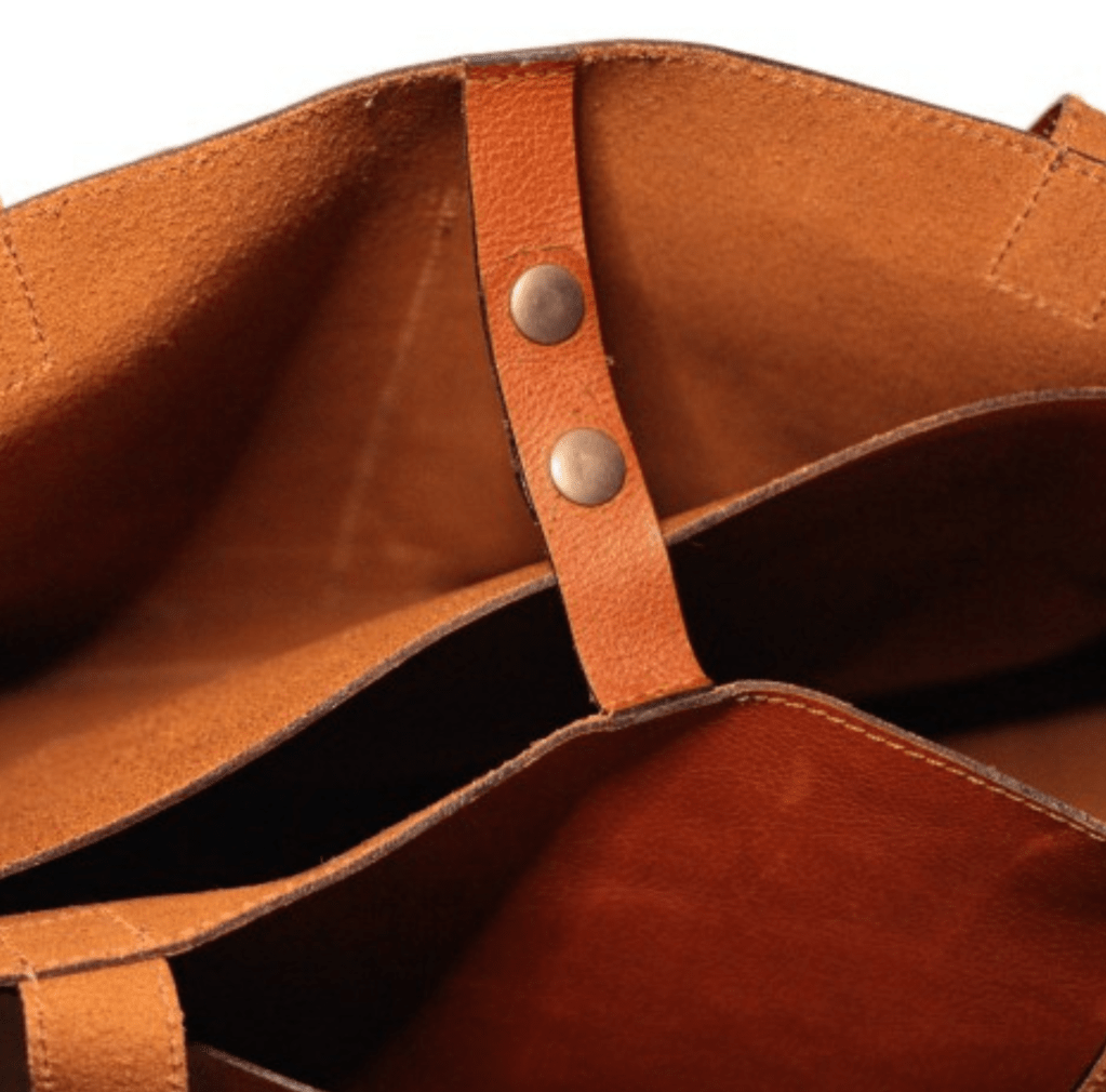 Interior of a tan leather bag with two handles, showcasing its spacious design.