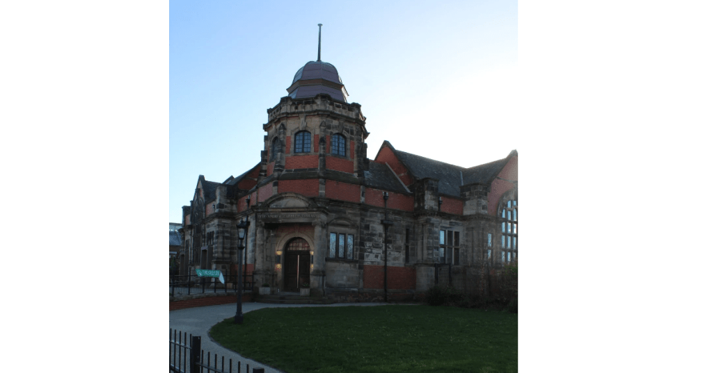 Historic library building: The Old Library, with a distinctive dome and intricate brickwork, set against a clear sky and green lawn.