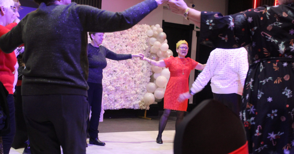 Guests joyfully dancing at a party, with vibrant balloons and cheerful decorations in the background.