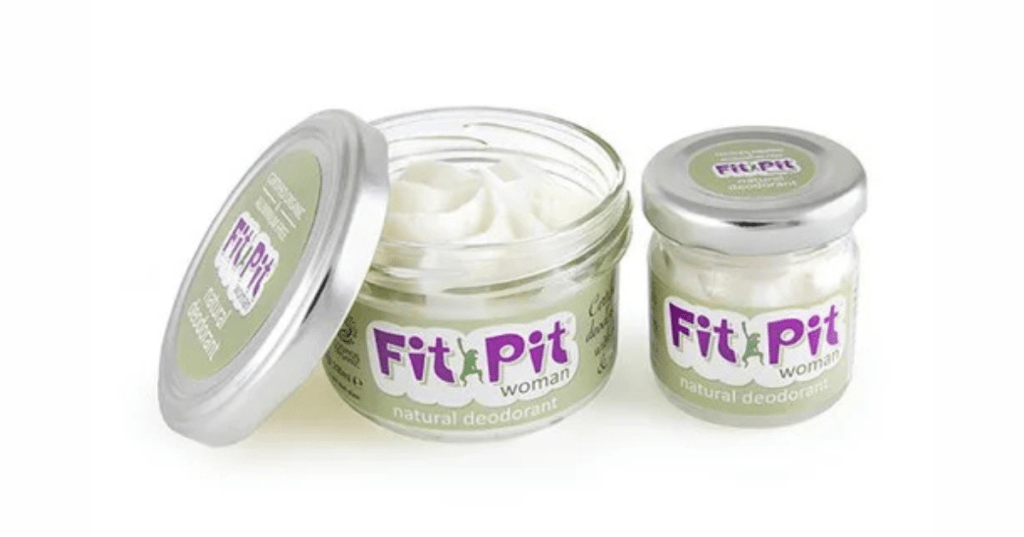 Two jars of Fit Pit Woman natural cream deodorant with light green labels and purple text. One jar is open, revealing a creamy white formula; the other is sealed. Branded for women, made with natural ingredients—ideal for Eco-conscious personal care.