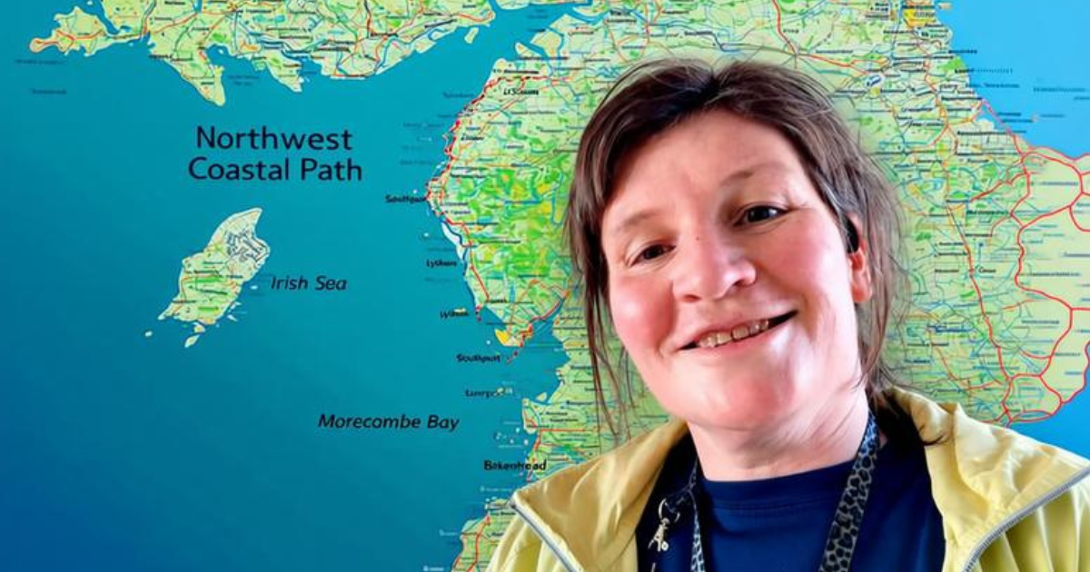 Alison Little standing in front of a detailed map of the North West Coastal Path, smiling as she plans to run the North West section of the route that stretches along the coastline from Chester to Gretna Green.